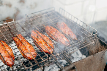 Traditional lula kebab cooking over hot embers on grill grate. Outdoor picnic meal with firewood...