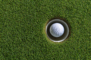 Golf ball perfectly placed in a lush green putting hole on a well-maintained course