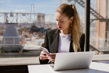 Businesswoman using smartphone and laptop in madrid cafe