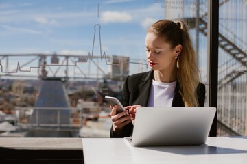 Businesswoman working remotely in madrid using laptop and smartphone