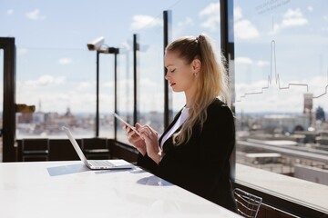 Businesswoman using smartphone and laptop on madrid rooftop terrace