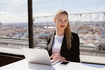 Businesswoman working on laptop with madrid cityscape in background