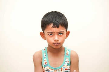 a cute indian asian boy of 5 years with gorgeous eyes and frowning unhappy facial expression