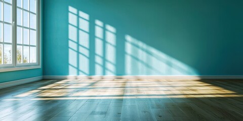 A bright, empty room with teal walls and sunlight casting shadows on the wooden floor, creating a serene and inviting atmosphere.