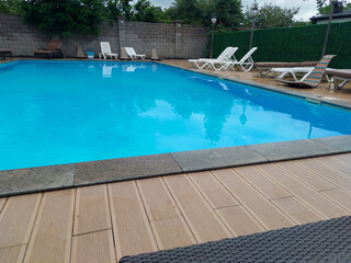 Drawing of a swimming pool, clear blue water, for relaxation, with facilities for lying and sitting, entertainment facility