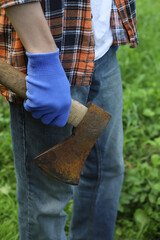 Work in the village. A guy in a checkered orange shirt and blue work gloves chops wood
