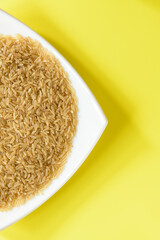 ARROZ (Oryza Sativa) SOBRE UN PLATO Y FONDO AMARILLO