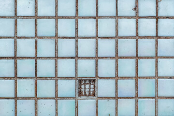 Pattern of pale blue iridescent square tiles with a single broken piece