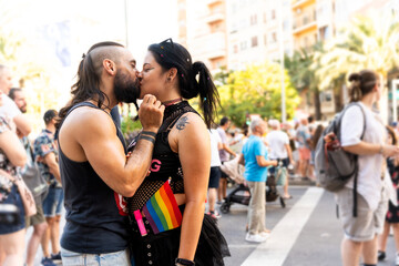 Couple kissing at gay pride parade showing rainbow flag