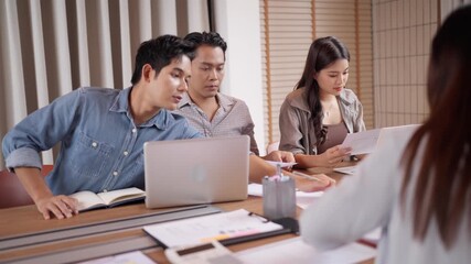 Asian business team analyzing data documents brainstorming ideas on laptop computers at modern office meeting table