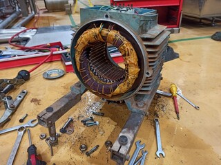 Close-up of a disassembled electric motor stator during maintenance, with copper windings visible...