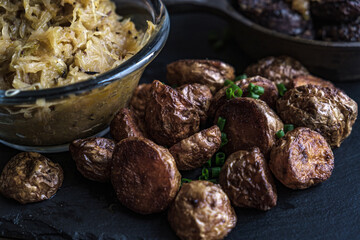 Traditional Polish food: kaszanka blood sausage with braised cabbage and roasted potatoes. Concept of rustic Eastern European cuisine in a dark, moody style.