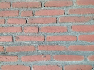 A rough, textured red brick wall with visible mortar joints, showcasing a classic and durable construction material.