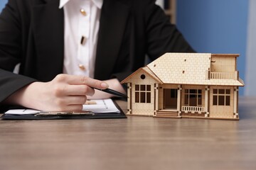 Real estate agent working at desk in office, focus on house model