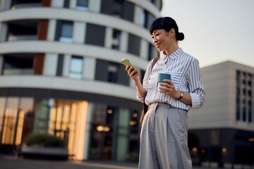 Asian Business Woman With Smartphone and Coffee Outdoors During Evening