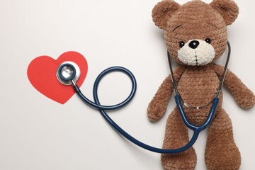 Pediatrics concept. Toy bear with stethoscope on white background, top view