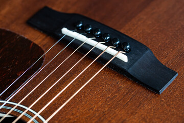 Closeup shot of the saddle of a brown wooden mahogany western guitar