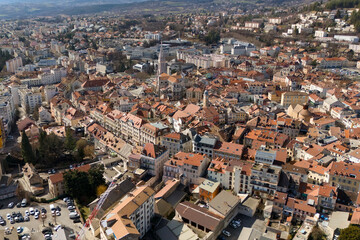 Aerial view of traditional residential rooftops in a southeastern French town with dense urban architecture and surrounding hills under clear sky