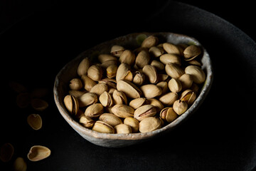 Front view pistachios in dark moody light on black background