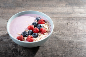 Healthy smoothie bowl with berries on wooden table. Copy space
