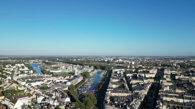 Aerial view of the river winding through the cityscape, contrasting with the dense urban landscape and the clear blue sky, Caen, Normandy, France.