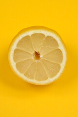 This vibrant shot showcases a single lemon half centered on a bright yellow background, highlighting its fresh texture and lively color