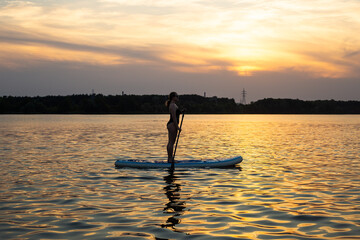 Young woman on stand up paddle board. Stand up paddle boarding on a quiet lake