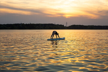 woman doing yoga on sup board at sunset. outdoor summer activity. Sup yoga. Social Distancing. copy...