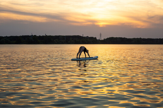 woman doing yoga on sup board at sunset. outdoor summer activity. Sup yoga. Social Distancing. copy space. Mental Health - Powered by Adobe
