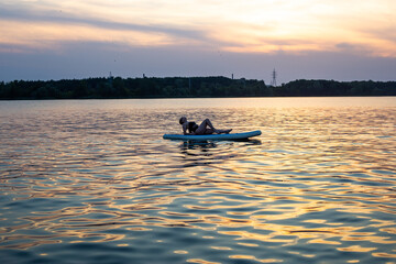 Woman practicing SUP yoga, relaxing on a paddle board. Woman on sup board.