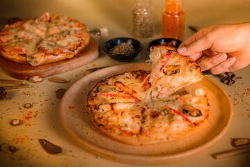 Pizza on a wooden plate placed on a table with a yellow background.