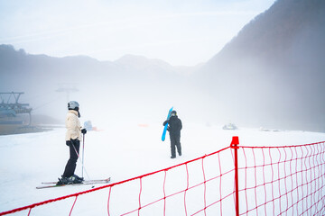 Two unrecognizable skiers with full gear on meet at the bottom of the slope.