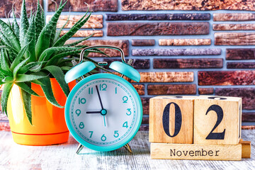 Wooden calendar with the date November 2.Monthly calendar for planning and management concept with alarm clock on wooden background