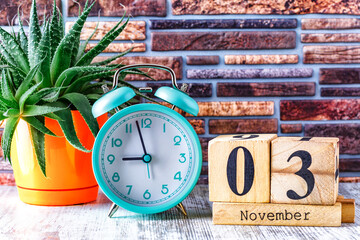Wooden calendar with the date November 3.Monthly calendar for planning and management concept with alarm clock on wooden background