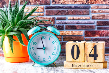 Wooden calendar with the date November 4.Monthly calendar for planning and management concept with alarm clock on wooden background