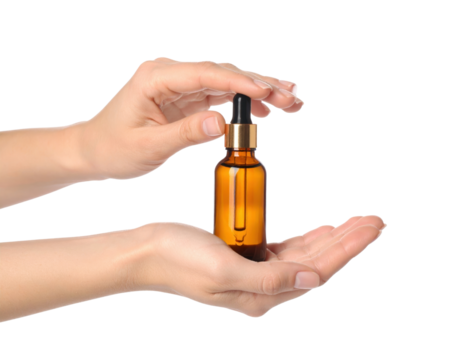 Two hands gently hold a small amber glass bottle with a dropper applicator containing clear liquid isolated on transparent background. PNG die-cut for advertising