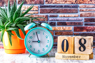 Wooden calendar with the date November 8.Monthly calendar for planning and management concept with alarm clock on wooden background
