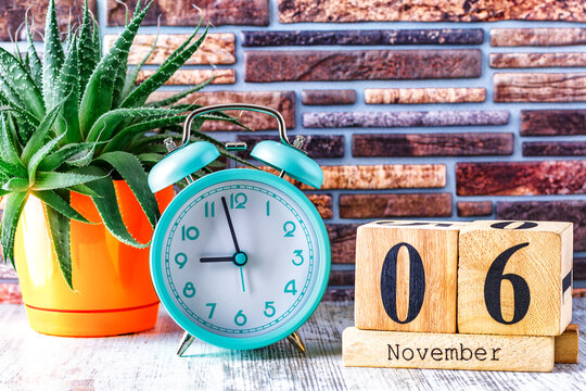 Wooden calendar with the date November 6.Monthly calendar for planning and management concept with alarm clock on wooden background