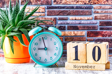Wooden calendar with the date November 10.Monthly calendar for planning and management concept with alarm clock on wooden background