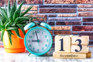 Wooden calendar with the date November 13.Monthly calendar for planning and management concept with alarm clock on wooden background