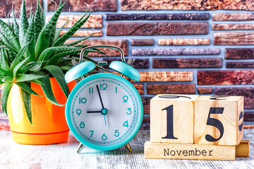 Wooden calendar with the date November 15.Monthly calendar for planning and management concept with alarm clock on wooden background