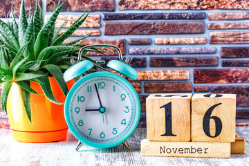 Wooden calendar with the date November 16.Monthly calendar for planning and management concept with alarm clock on wooden background