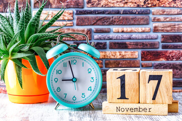 Wooden calendar with the date November 17.Monthly calendar for planning and management concept with alarm clock on wooden background