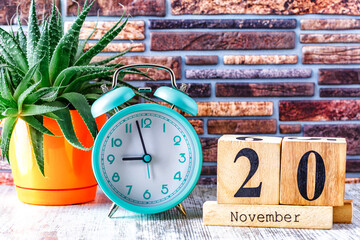 Wooden calendar with the date November 20.Monthly calendar for planning and management concept with alarm clock on wooden background