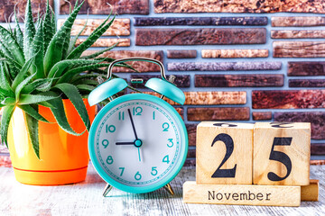 Wooden calendar with the date November 25.Monthly calendar for planning and management concept with alarm clock on wooden background