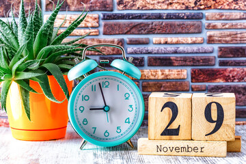 Wooden calendar with the date November 29.Monthly calendar for planning and management concept with alarm clock on wooden background