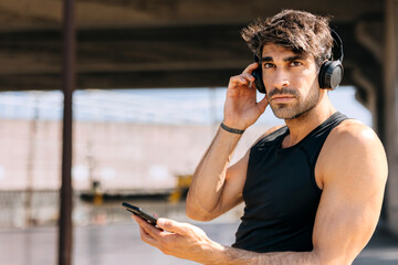 Hispanic man enjoys music while preparing for an outdoor workout in the city