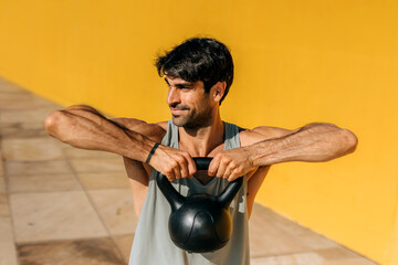 Hispanic man engaged in kettlebell workout, demonstrating strength and focus in an outdoor fitness...