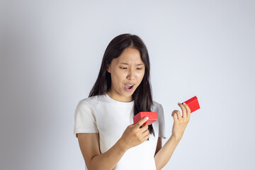 A young woman looking surprised or excited as she opens a small red gift box.