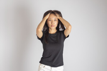 A young asian woman with dark hair, standing against a plain light-colored 